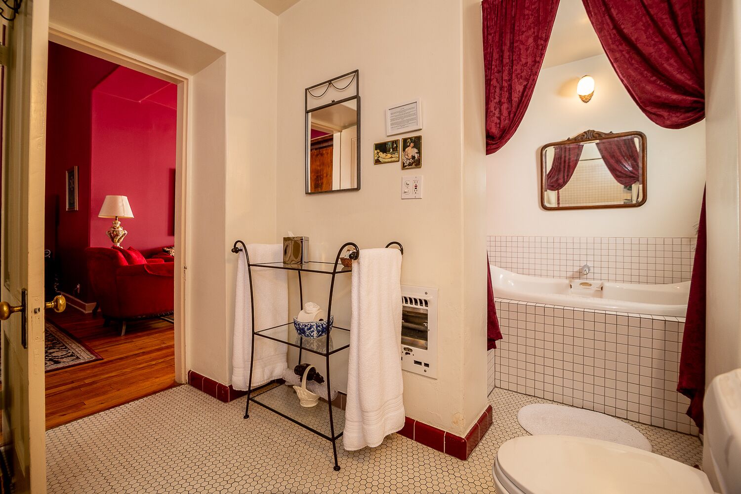 A bathroom with a white sink, a bathtub, and a toilet. There is a towel rack with white towels and a mirror above it.
