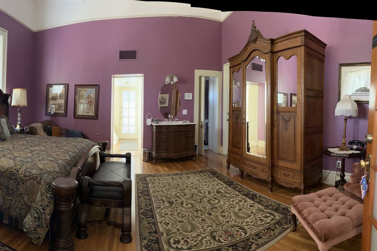 Une chambre à coucher avec un grand lit, une commode, une coiffeuse et un miroir.