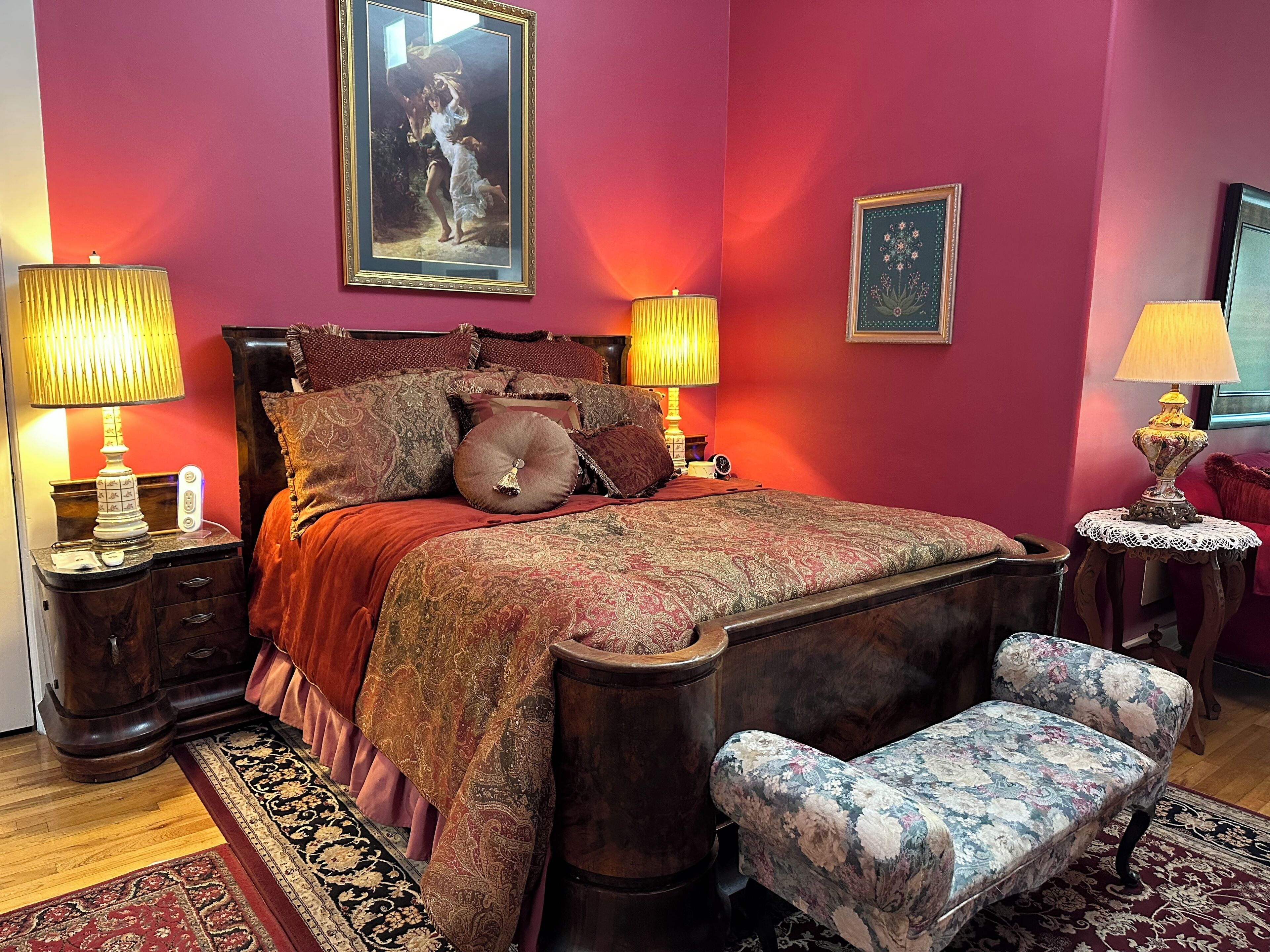 Un dormitorio con una cama grande, dos lámparas de noche, una mesita de noche, una silla y un cuadro en la pared.