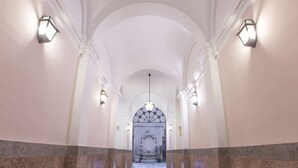 Ein Flur mit gewölbter Decke und Wandleuchtern.