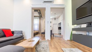 A modern living room with a sofa, coffee table, and a TV mounted on the wall. - Real Apartments Zichy (Budapest)