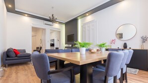 A modern dining area with a wooden table, blue chairs, and a chandelier. - Real Apartments Zichy (Budapest)
