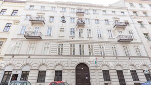Un edificio a più piani con un ingresso centrale, balconi e una bandiera.