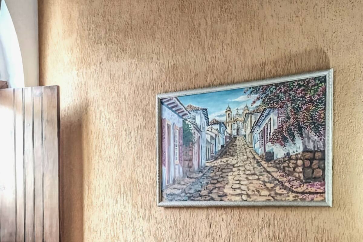 Une chambre d’hôtel avec deux lits, chacun recouvert d’une couvre-lit rose et blanche, et un tableau représentant une scène de rue accroché au mur.