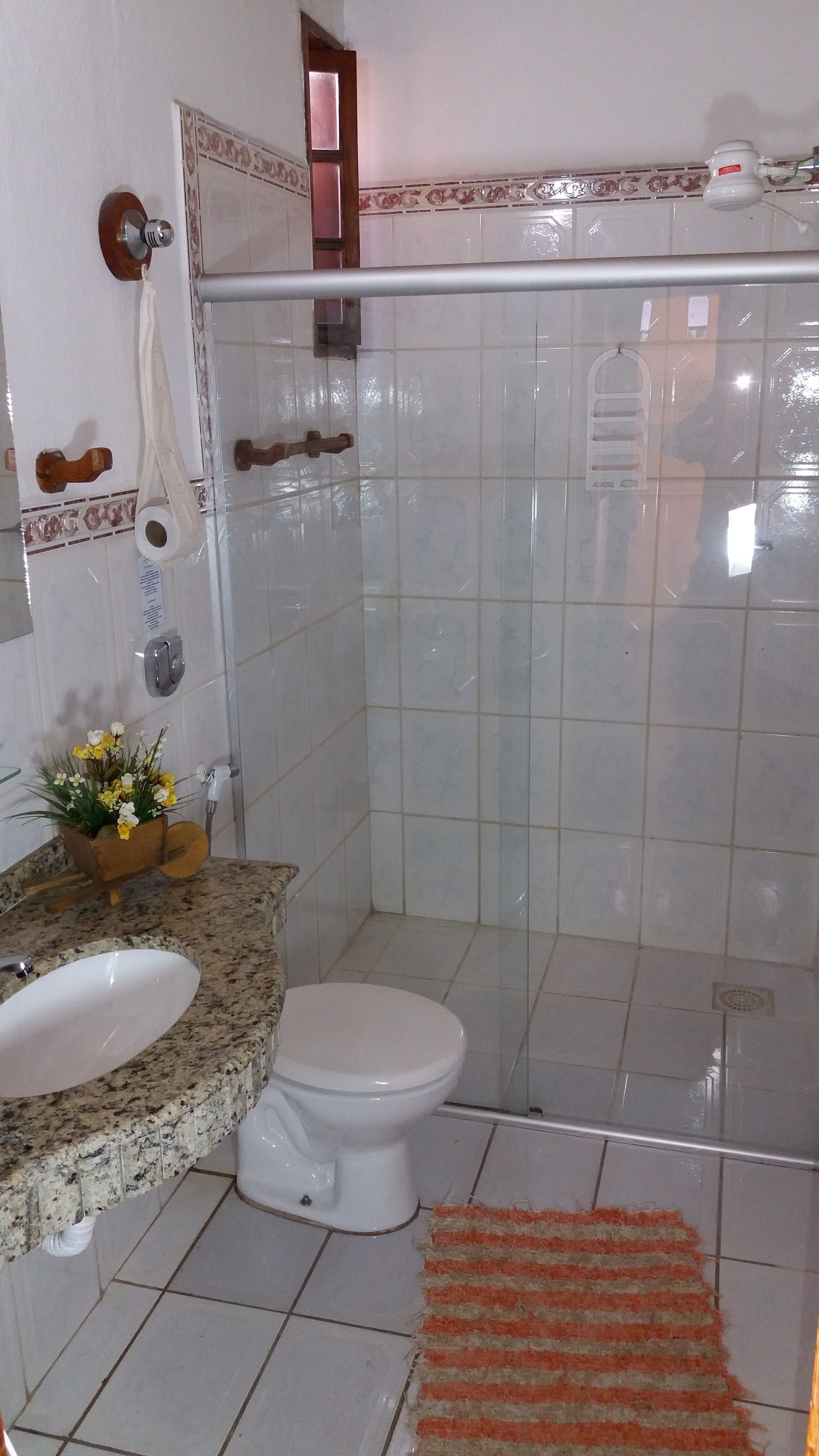 A bathroom with a granite countertop, white sink, toilet, and shower stall.