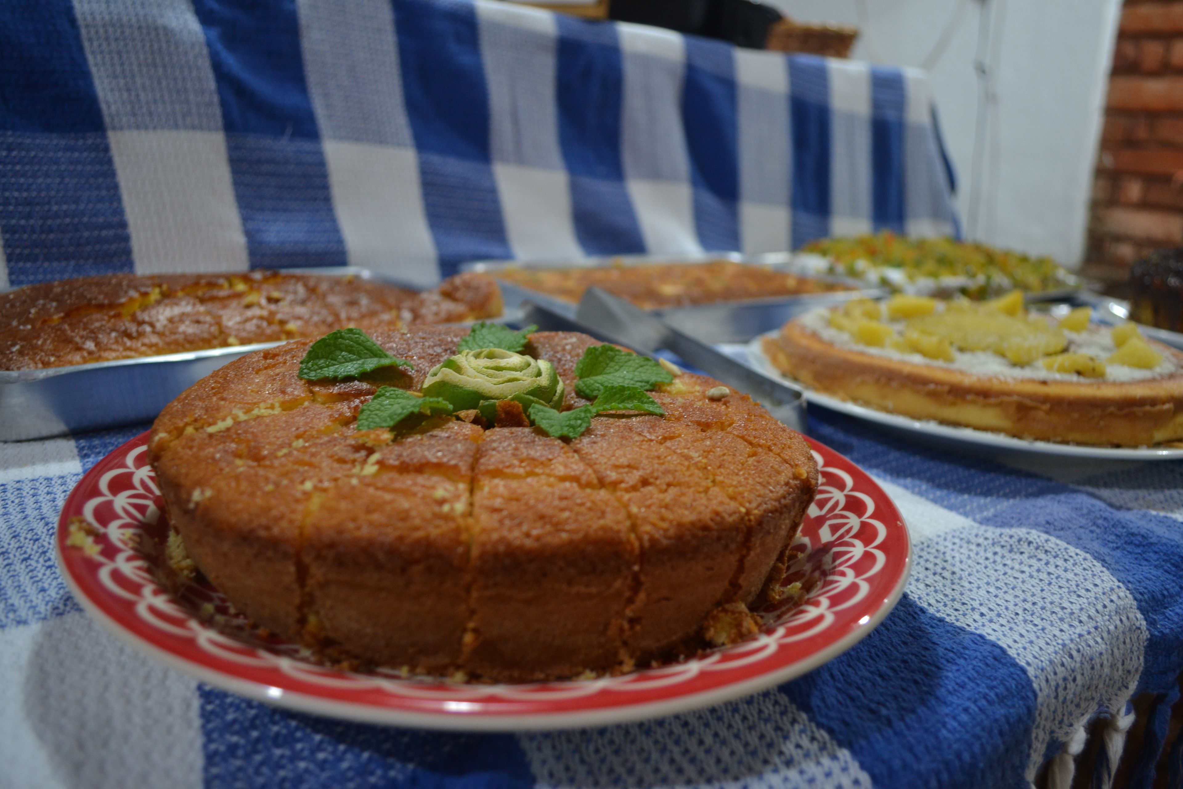 Un pastel redondo con hojas de menta sobre un plato, sobre un mantel a cuadros.