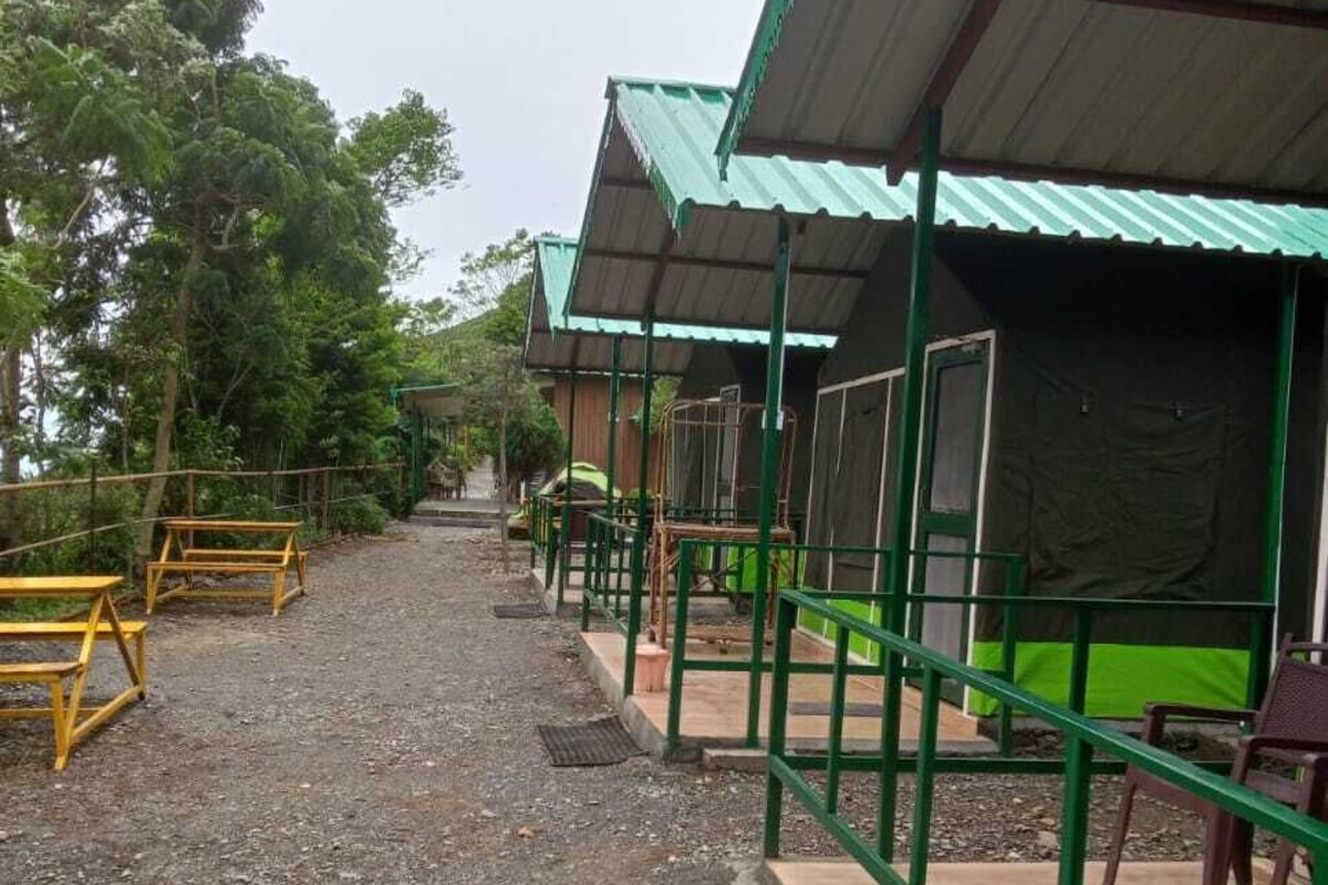 A pathway leading to a building with a green roof and a covered outdoor seating area.