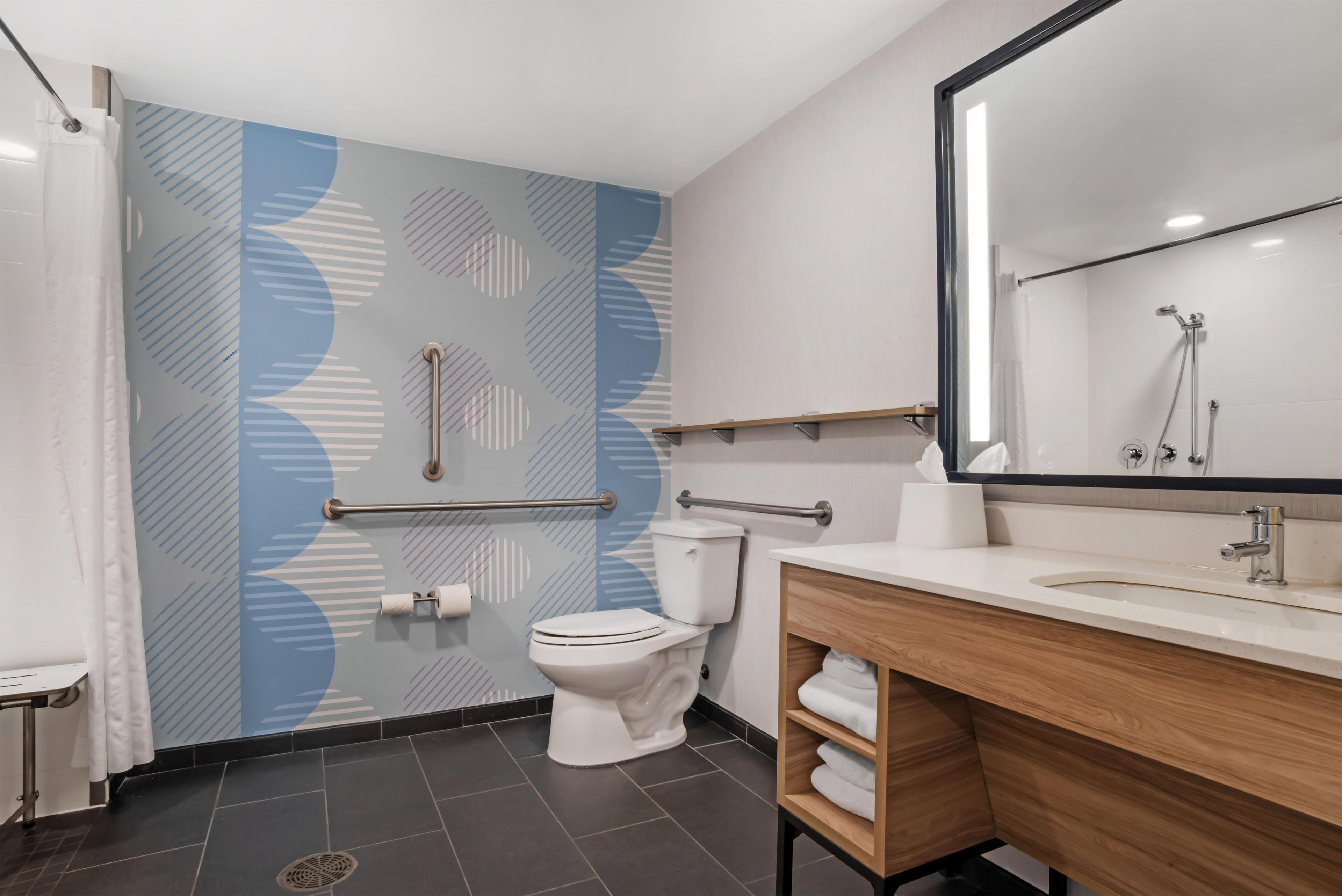 A modern bathroom with a toilet, a sink, a mirror, and a shower area.
