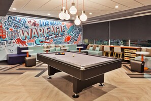 A pool table in a lounge area with a mural featuring sports and entertainment themes. - Tru by Hilton Auburn (Auburn)