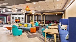 Un espacio lounge moderno con asientos de colores, mesas y lámparas colgantes.
