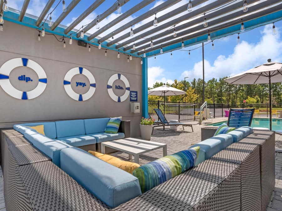 A covered outdoor seating area with a pool, lounge chairs, and umbrellas.