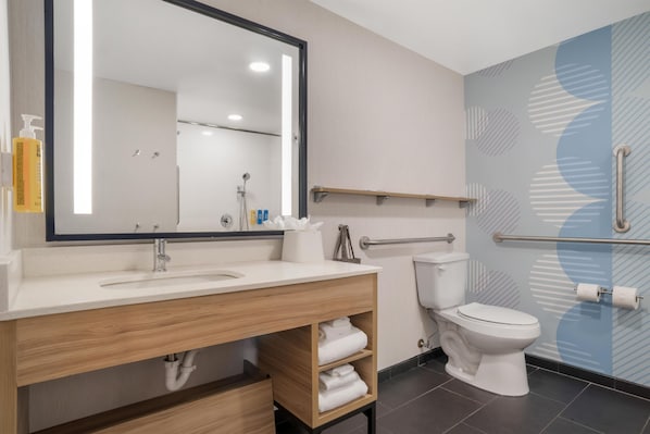 Un baño moderno con un espejo grande, un lavabo, un inodoro y una zona de ducha.
