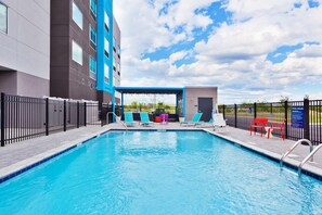 A swimming pool with lounge chairs and a covered seating area.