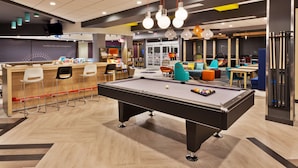 Un espacio interior moderno con mesa de billar, zona de bar y diferentes disposiciones de asientos.