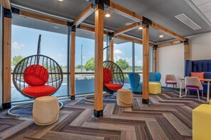 Un interior moderno con sillas colgantes, un sofá azul y vistas al exterior.