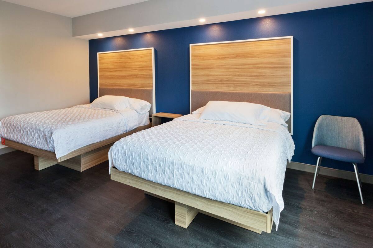 Two single beds with wooden frames and headboards, a small bedside table, and a chair.