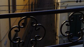 Une rue étroite, bordée de bâtiments de chaque côté, avec des balcons et des volets.