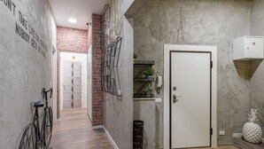 Un couloir avec un mur en briques, une porte blanche et un escalier doté de rampes en métal.