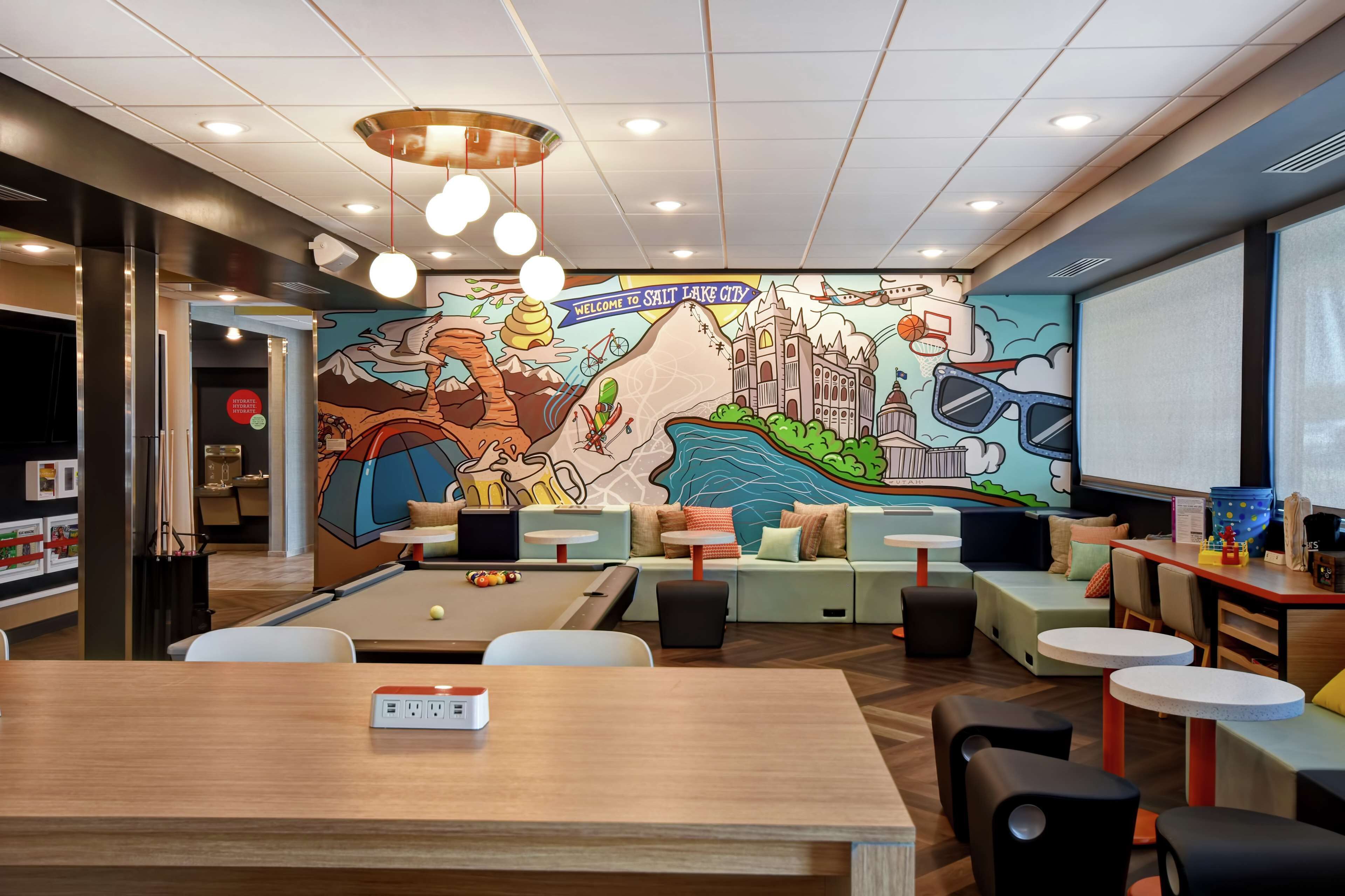 A modern lounge area with a mural, comfortable seating, and a projector screen.