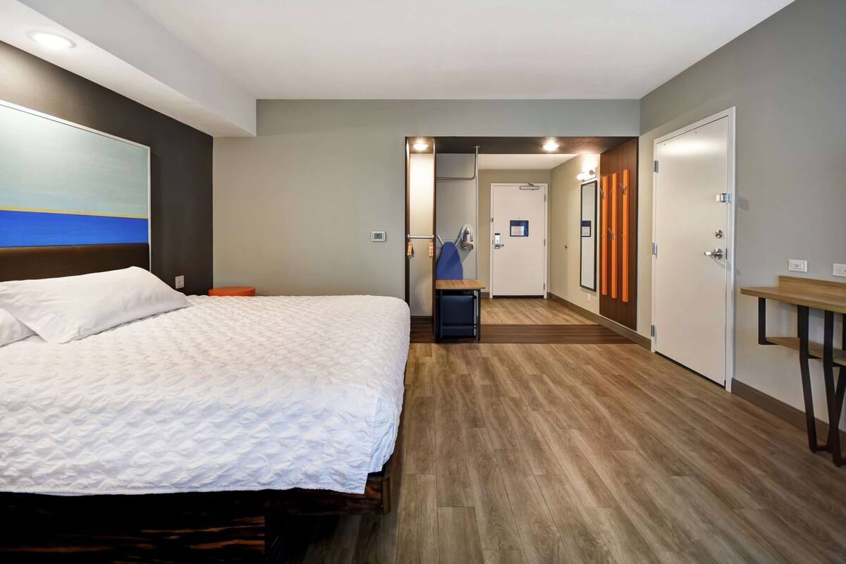 Ein Hotelzimmer mit einem Bett, einem Schreibtisch und einem durchgegangenen Tür erkennbaren Badezimmer.