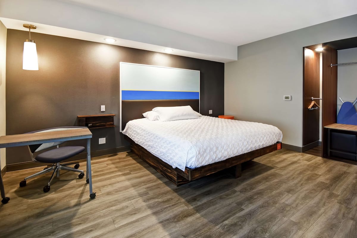 Une chambre d’hôtel moderne avec un lit en bois, un bureau et une chaise.