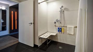 A modern bathroom with a shower, a towel rack, and a small bench.