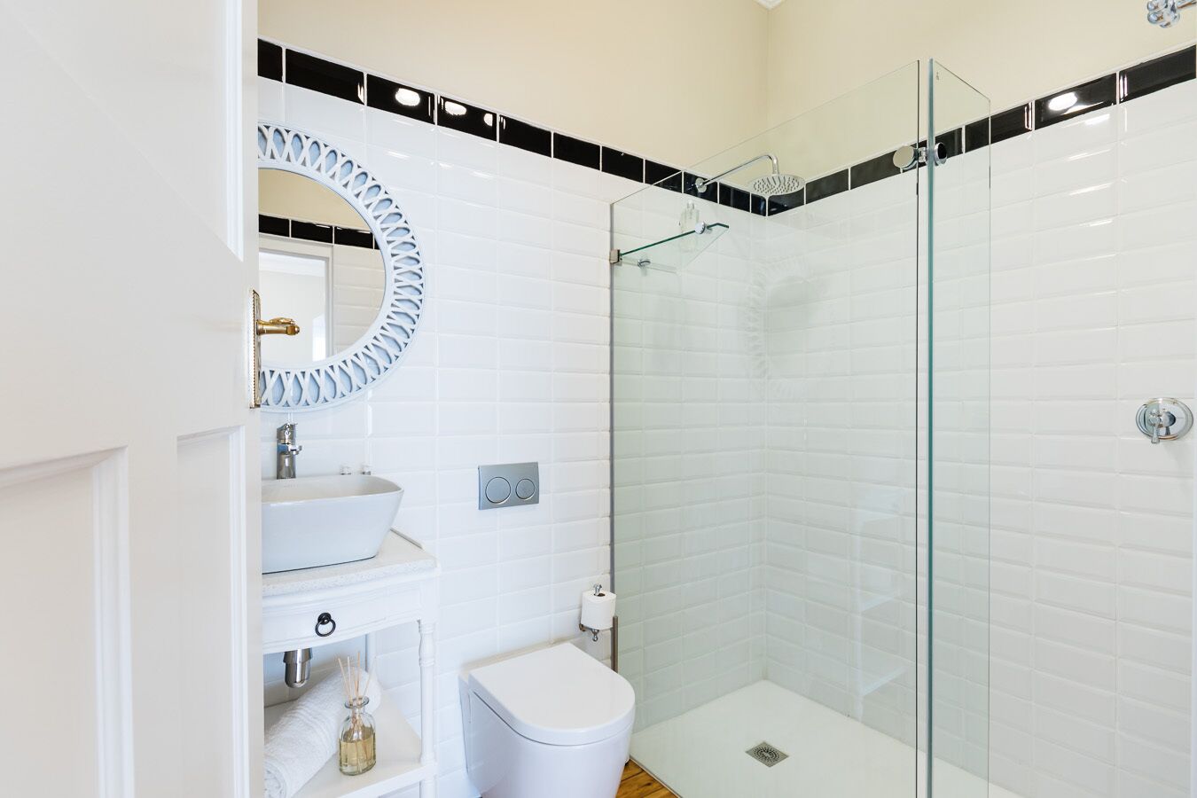 A modern bathroom with a glass-enclosed shower, a white sink, and a large mirror with a decorative frame.