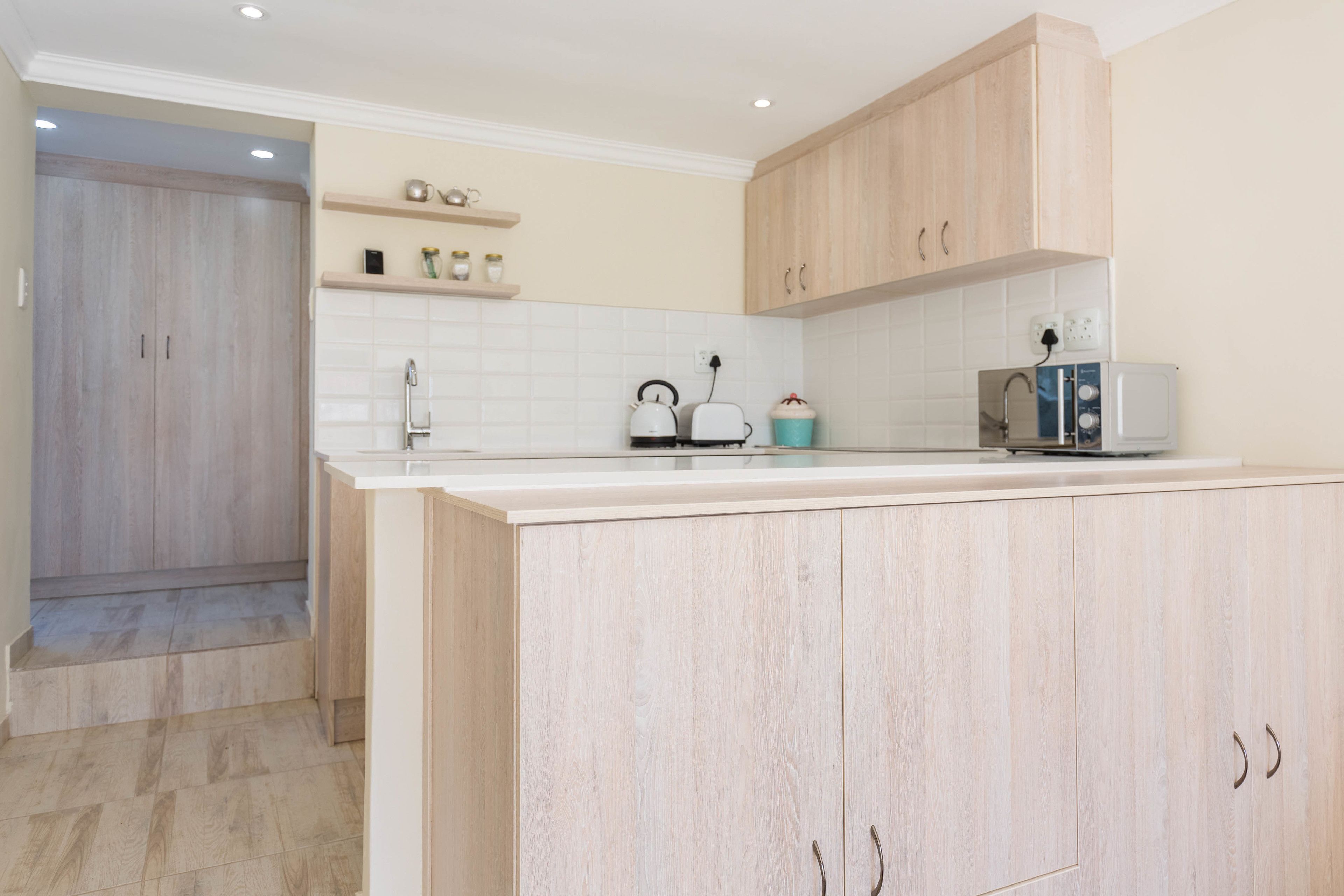 Een moderne keuken met lichte houten kastjes, een wit aanrechtblad en een inbouwoven.