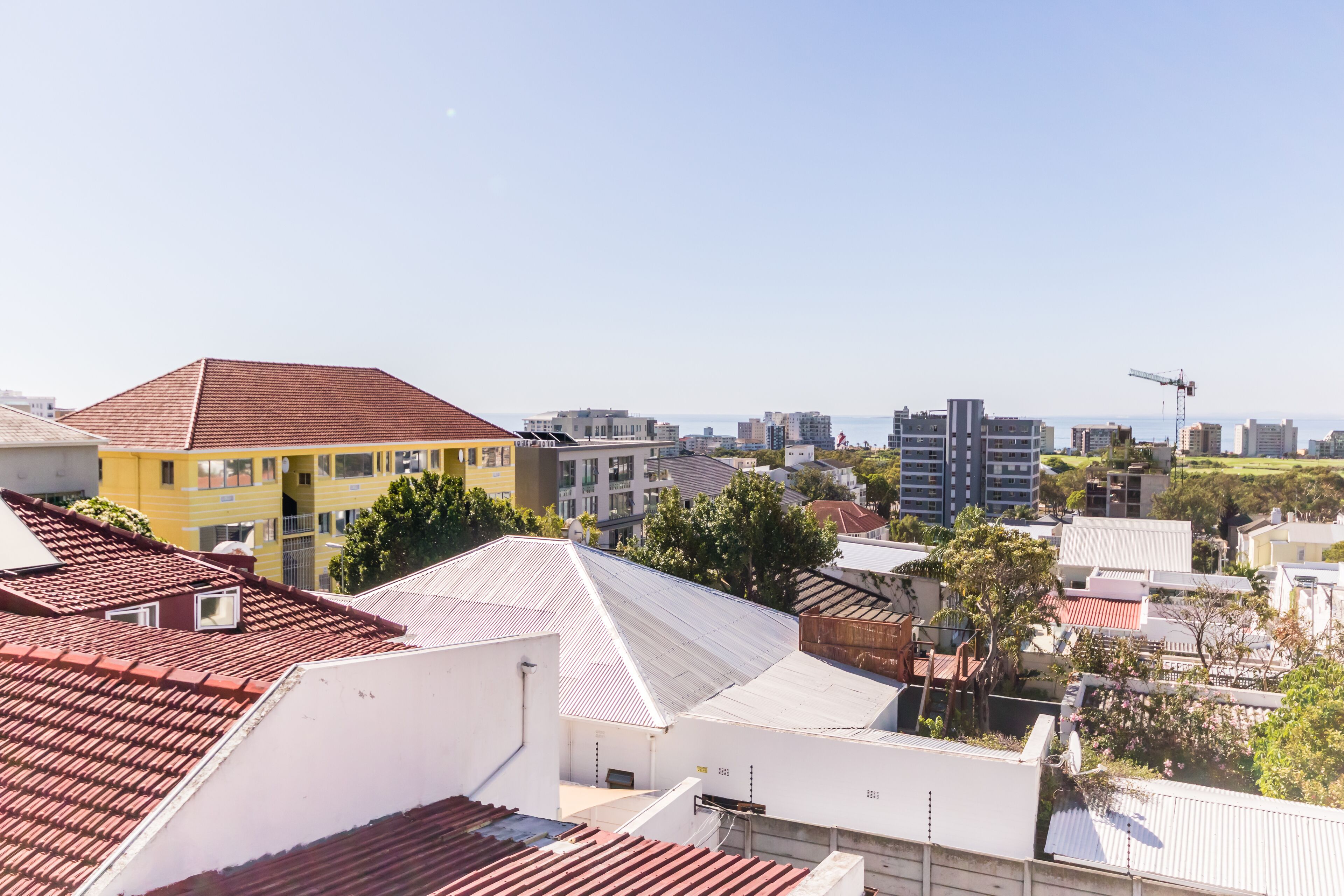 Ett bostadsområde med olika typer av byggnader, bland annat ett gult hus med rött tak och en vit byggnad med vitt tak.