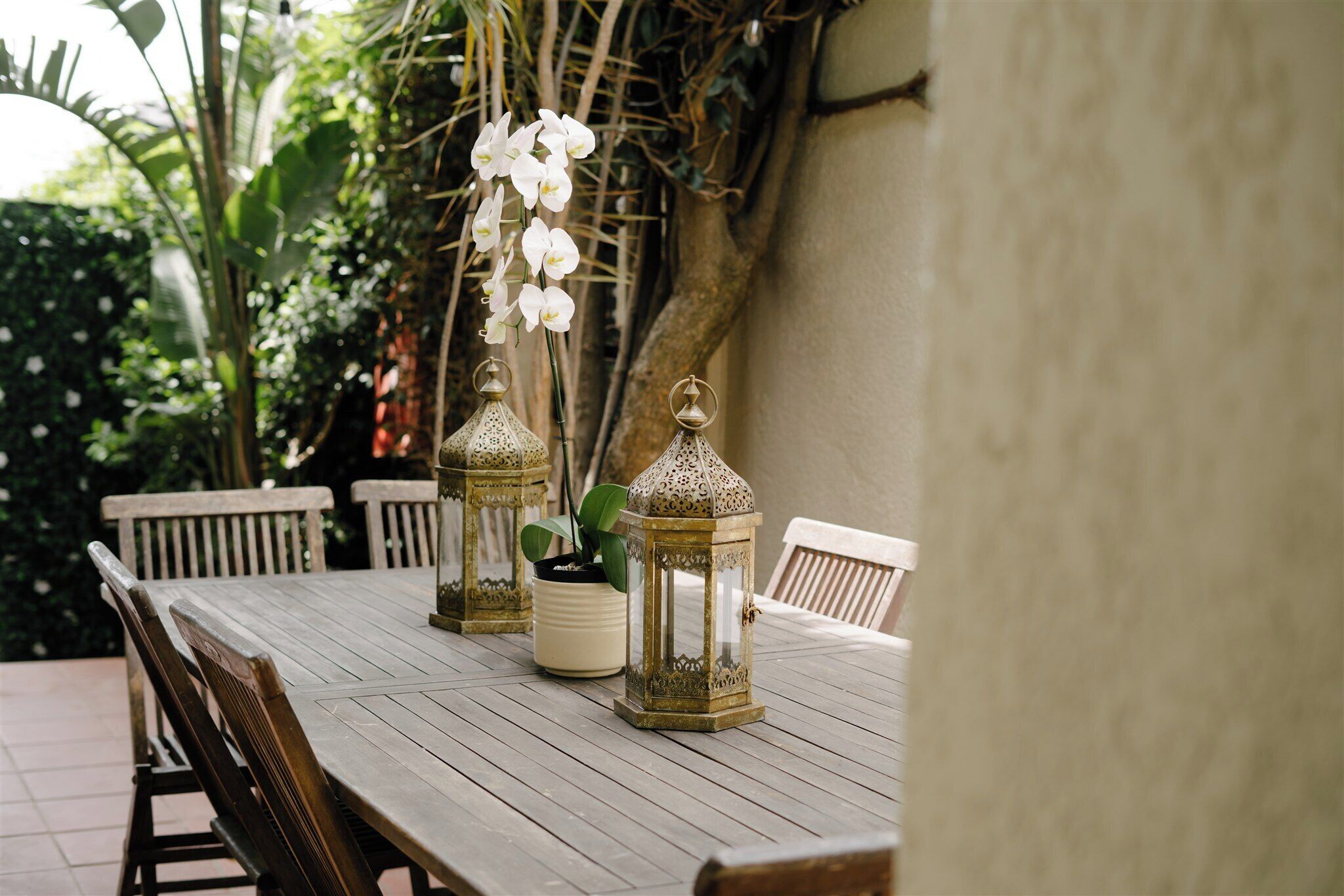 A wooden table with two ornate lanterns and a potted plant.