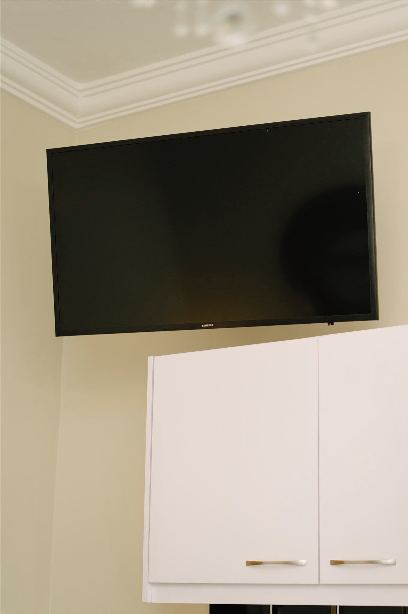 A flat-screen TV mounted above a white cabinet with two doors.