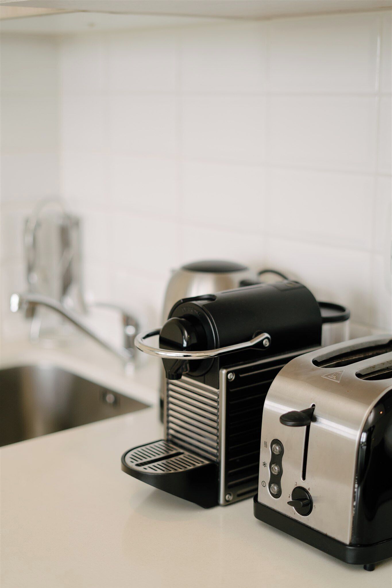 Una cocina con tostadora, cafetera y lavamanos.