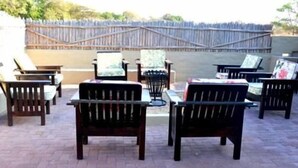An outdoor patio area with several wooden chairs and a table, surrounded by a wooden fence. - Senate Boutique Camp - Campsite (Hoedspruit)