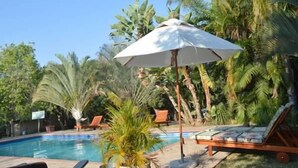 Ein Poolbereich mit Liegestühlen und einem Sonnenschirm.