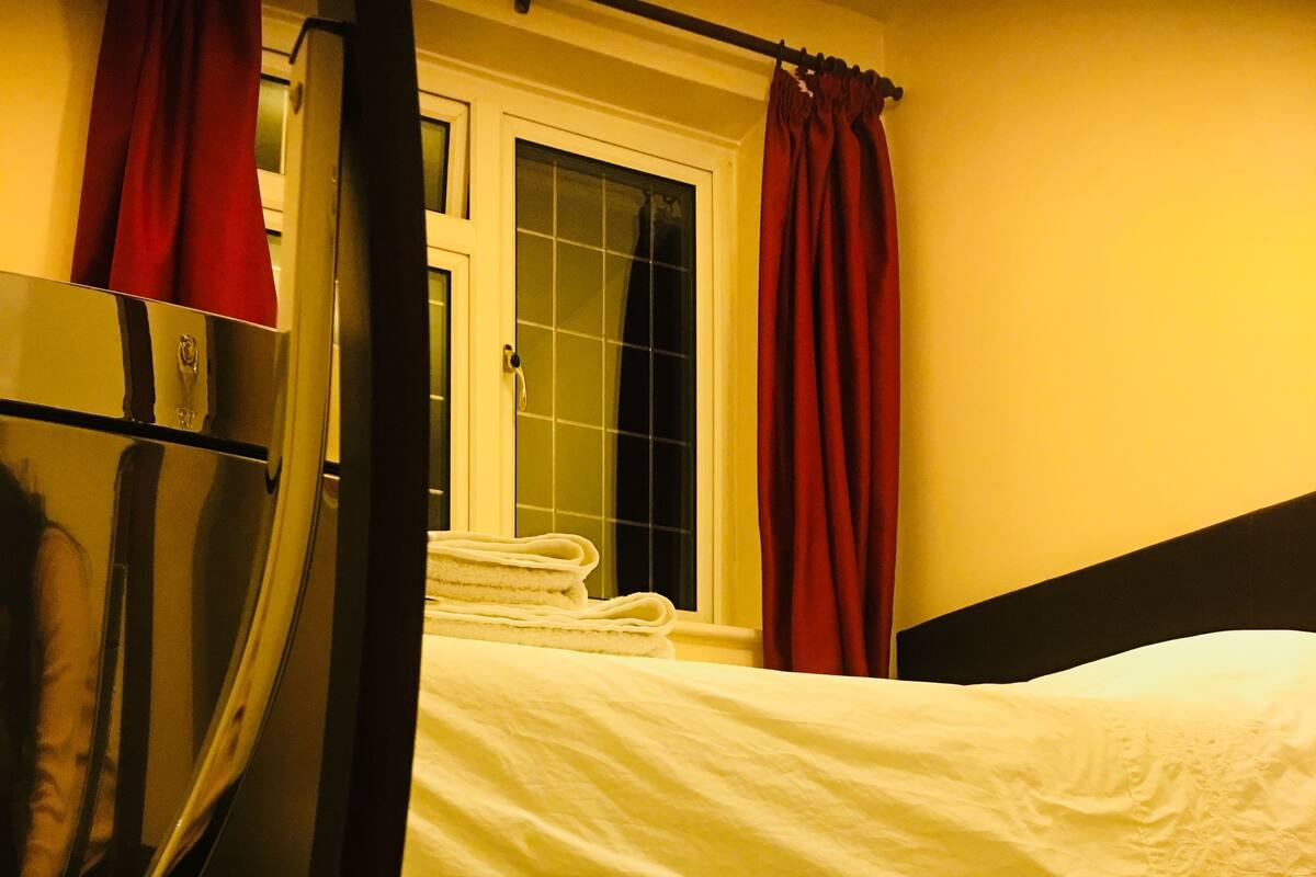 A hotel room with a bed, a mirror, and a window with curtains.