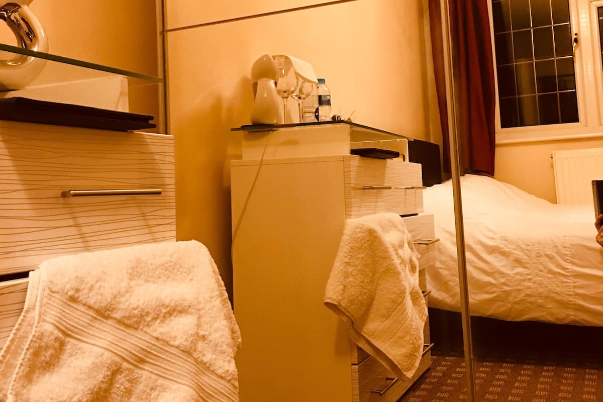 A hotel room with a bed, a dresser, a mirror, and a window with curtains.