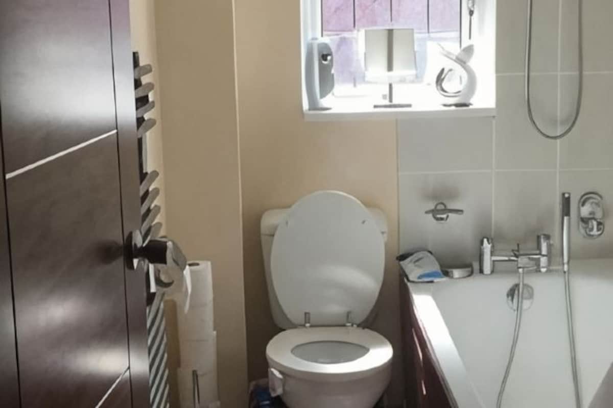 Un baño con inodoro, bañera, ducha y ventana con vistas.