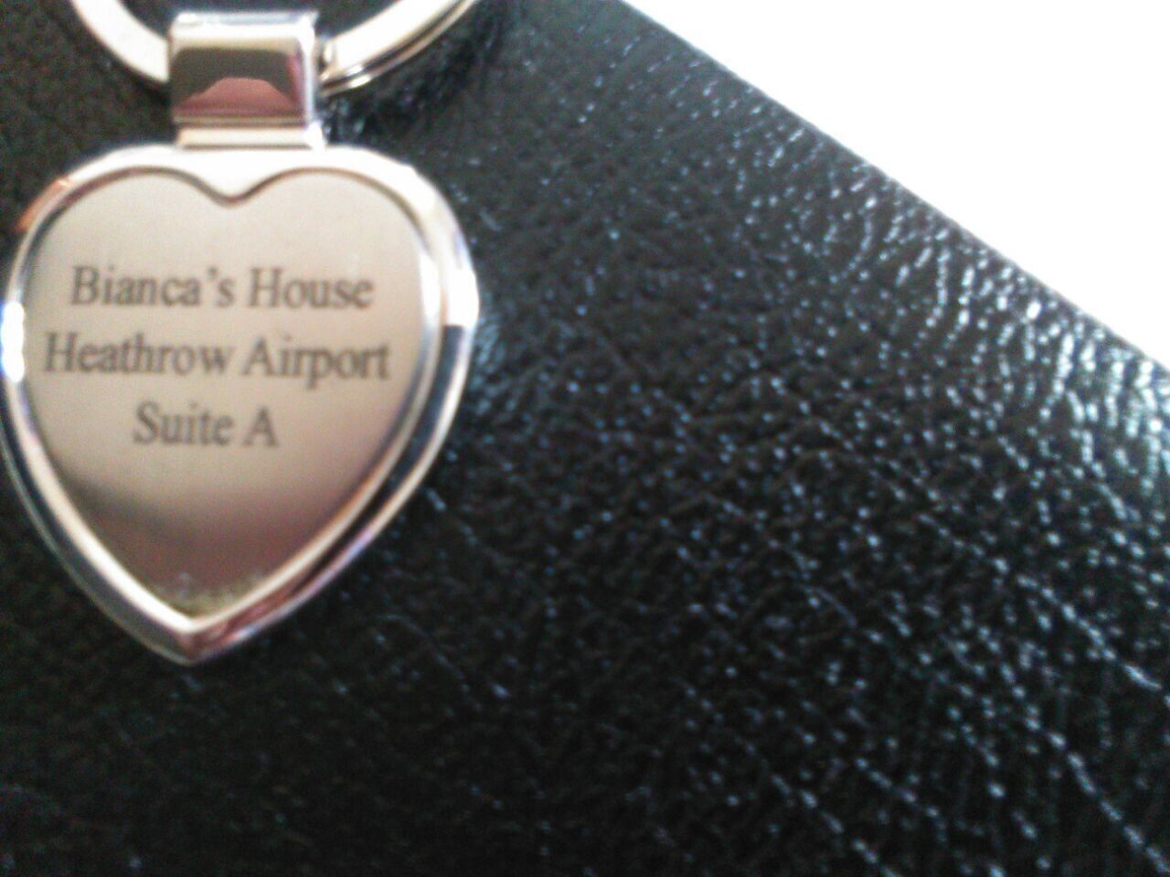 A heart-shaped keychain with text reading "Bianca's House Heathrow Airport Suite A".