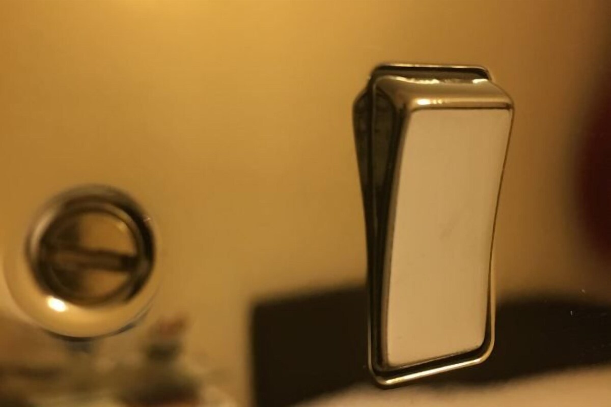 Primer plano de un objeto metálico con superficie reflectante, posiblemente parte de un mueble o equipo.