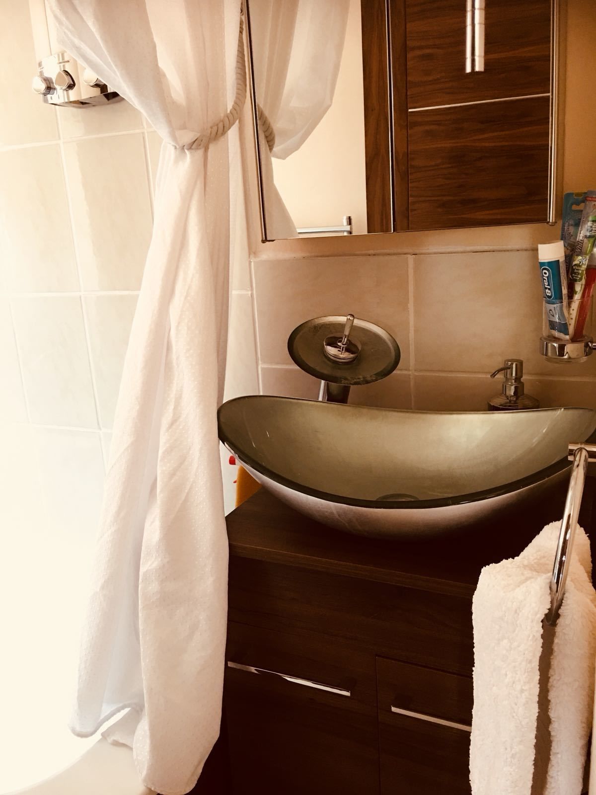 Une salle de bain avec un lavabo moderne, un rideau de douche et un miroir.