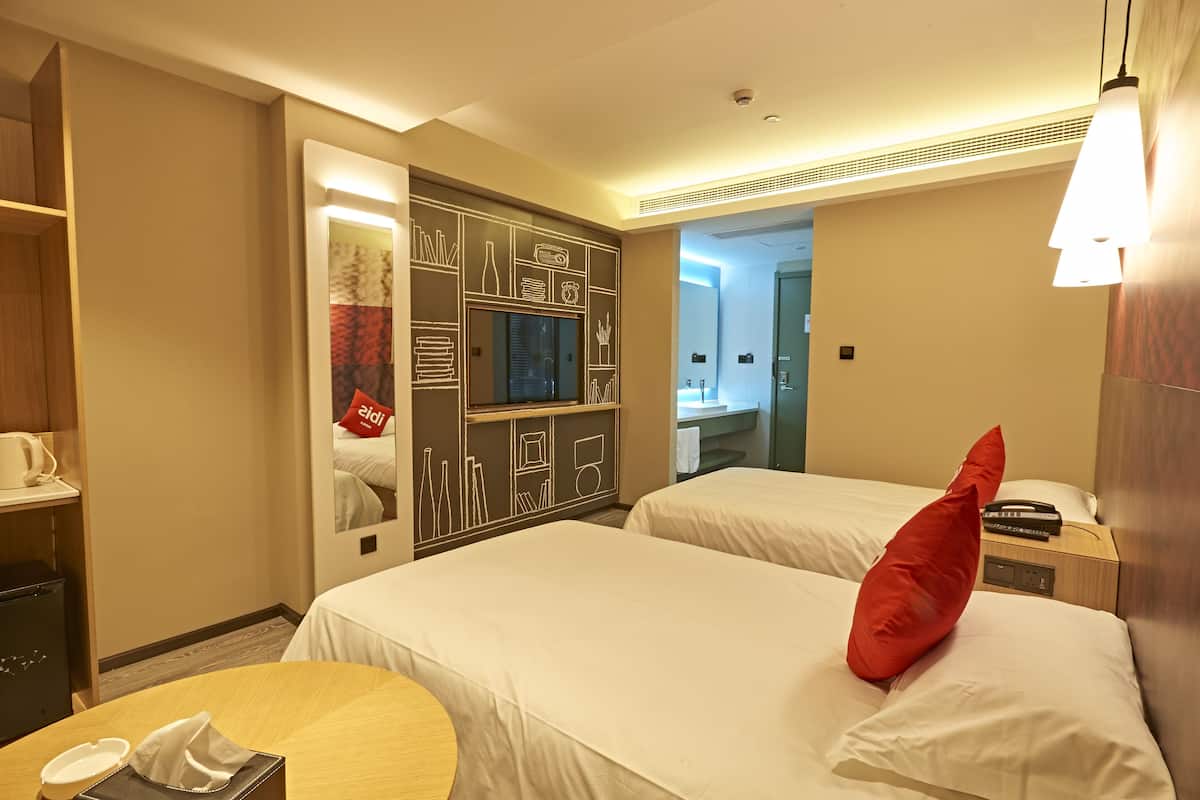 A hotel room with two beds, a desk, and a minibar.