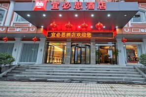 Ein Hotel Eingang mit einem Schild, das "宜必思酒店欢迎您" zeigt, und traditionellen roten Laternen darüber.