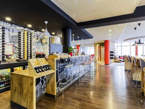 Un espace bar moderne avec un comptoir en bois, des bouteilles de vin et un présentoir pour les menus.