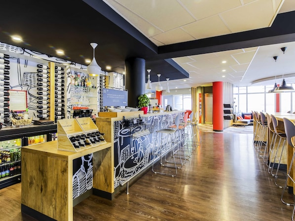 A modern bar area with a wooden counter, wine bottles, and a menu display.