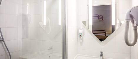 Un baño moderno con cabina de ducha de vidrio, un lavabo blanco y un secador de pelo montado en la pared.