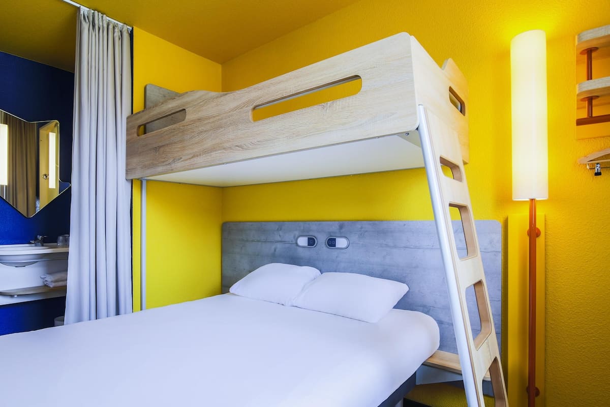 Un lit superposé avec une tête de lit en bois, une table de chevet et une lampe.