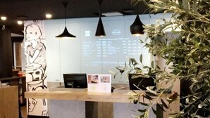 Una recepción de diseño moderno, una planta grande en maceta y una pared con un menú.