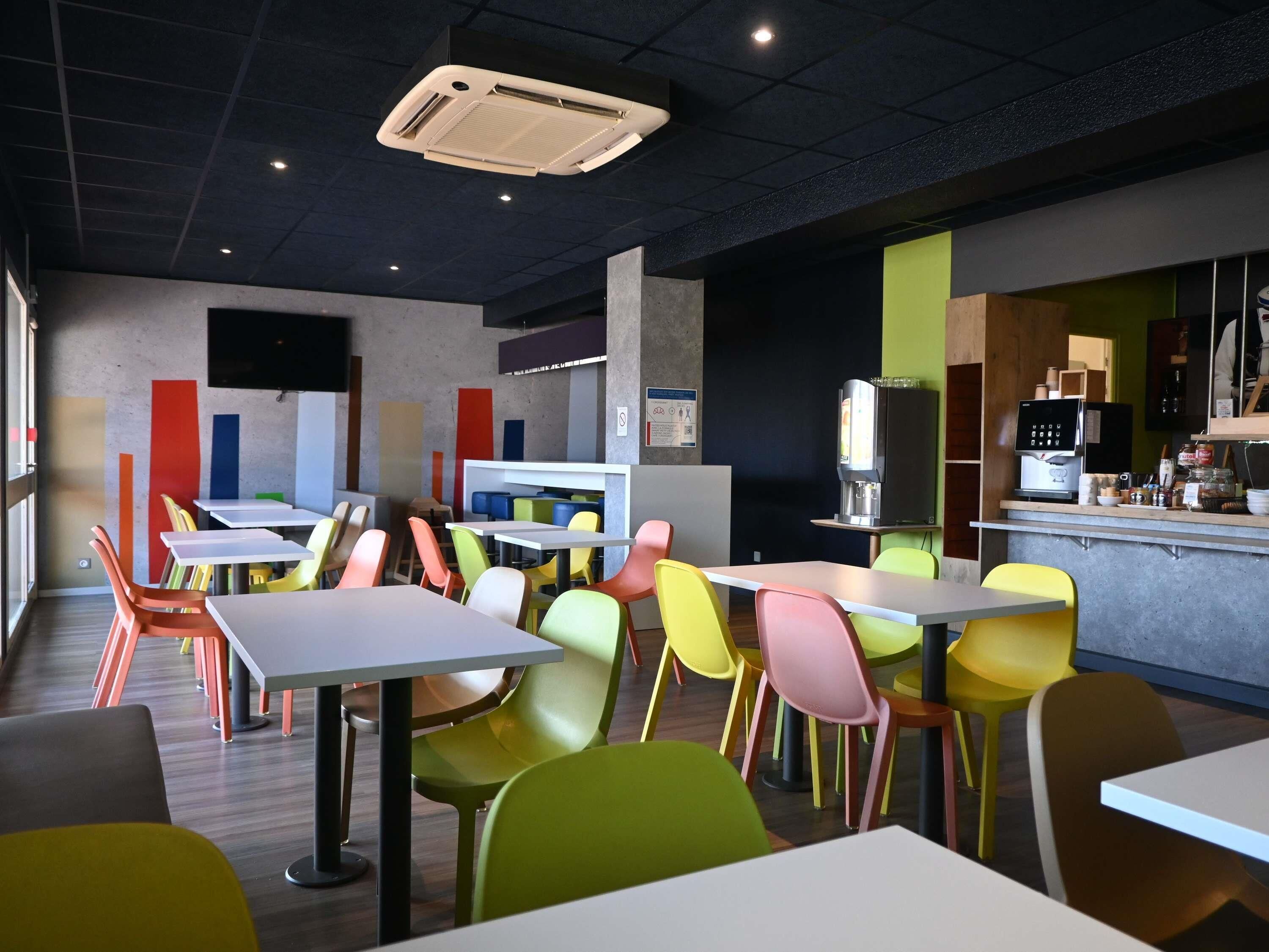 A modern cafe interior with colorful chairs, tables, and a coffee machine.