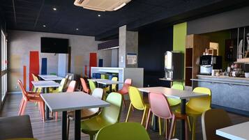 A modern cafe interior with colorful chairs, tables, and a coffee machine.