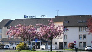 Un hôtel avec une enseigne indiquant « hôtel ibis budget » et un parking avec des voitures.